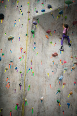 Young asian girl indoor rock climbing