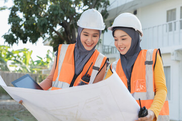 Two Asian female muslim engineer worker wear hijab working and discuss about structure home...