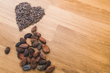 Premium cocoa beans and a heart made of chocolate chips on a wooden surface. High quality photo
