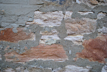 Close Up of Rough Textured Surface of Old Stone Wall with Cement Repairs 