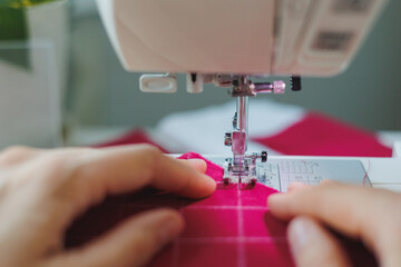 woman sews clothes or accessories from pink fabric in workshop. creative sewing studio, top view, closeup, handmade designer fashion house atelier. women's small business and home office work