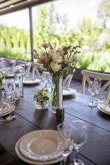 A very nicely decorated wedding table appointments with beautiful decor with plates and serviettes in spring garden. Beautiful flowers on table in wedding day. The elegant dinner table.