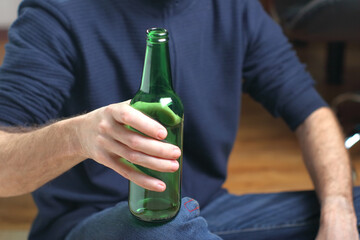 a person holding a green beer bottle