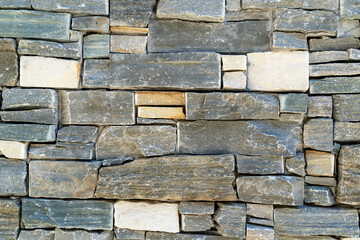 A wall made by stacking small stone slabs on top of each other. beautifully and organized in an orderly fashion.