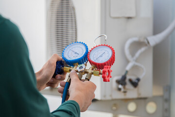 Air conditioning, HVAC service technician using gauges to check refrigerant and add refrigerant.