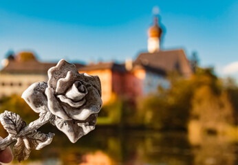 Obraz premium Details of a beautiful stone rose with reflections and a monastery at the famous Hoeglwoerther See lake, Berchtesgadener Land, Bavaria, Germany