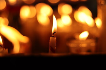 Solitary candle with others around it consuming itself with yellow and red flame white candle with...
