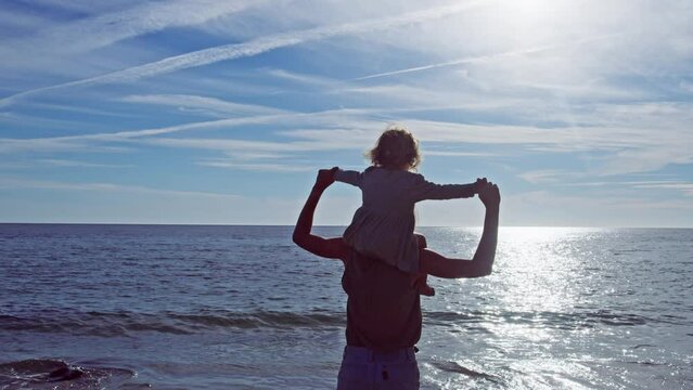 Mother carry little girl on shoulders, turn, spin at sea beach