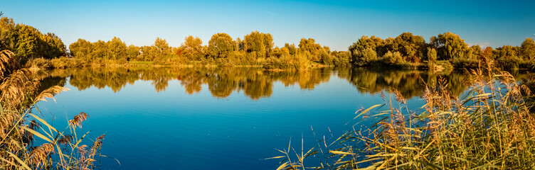 High resolution stitched autumn panorama with reflections in a pond near Wallersdorf, Bavaria, Germany