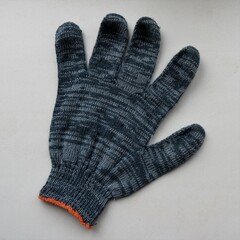 fabric glove made of gray-blue cotton material isolated on a light surface, one protective glove made of soft fabric lying on a plane close-up