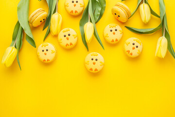 Set of easter macaroon chicks with yellow tulips over yellow background. Top view, flat lay, copy space. Easter background or greeting card. Holiday symbol