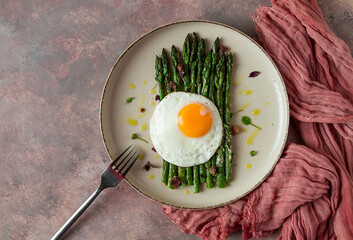 grilled asparagus, with fried egg, spices and herbs, parmesan cheese, on a beige plate, top view, rustic, no people
