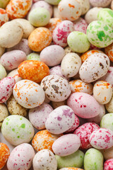 Easter background made of multicolored candy chocolate eggs. Overhead view, close up. Festive food background. Holiday symbol