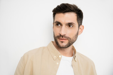 Portrait of brunette man in shirt looking away on white background.
