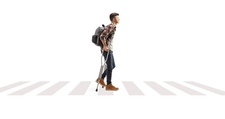 Male student walking with crutches on a pedestrian crossing