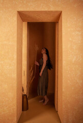 A woman wearing dress in a beige sandstone room. warm and cozy atmosphere.