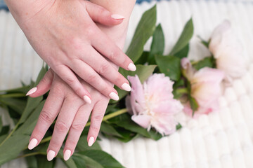 Obraz na płótnie Canvas girl's hands with a beautiful pink manicure design,pastel color, gently, flowers