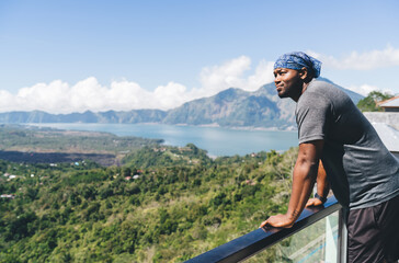 Black man on balcony observing mountains in sunlight