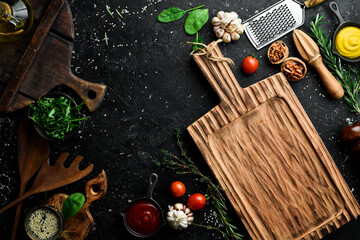 Cooking background. Kitchen board, vegetables and spices. On a black stone background. Top view.