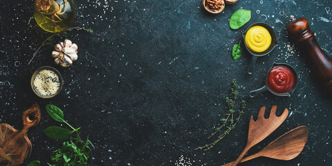 Cooking background. Spices, vegetables and herbs. On a black stone background. Top view.