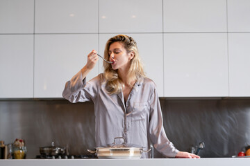 Girl with cooking pot, doing housework. Housekeeping concept. Beautiful woman stands near table on kitchen at home. Housewife cooking on the kitchen in the morning.