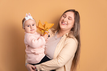 cheerful baby girl and mom offering easter egg in beige background. holiday, easter, celebration concept.