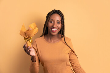 joyful brazilian woman smiling and looking at camera in beige studio background. holiday, easter, celebration concept.