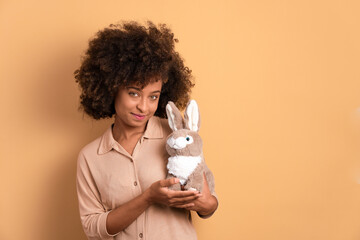 happy african american woman with easter bunny in all beige colors. holiday, easter, celebration concept.