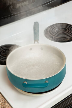 Steam Rising From Boiling Water In Pan On Stove Vertical