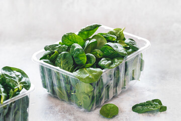 Fresh baby spinach in a plastic package on table.  Green salad,  baby spinach leaves box, selective focus