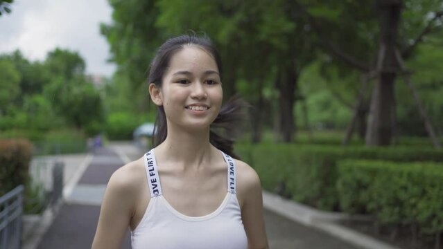 Portrait of Asian woman girl in yoga class club doing exercise, runing or jogging at public garden park. Outdoor sport and recreation. People lifestyle activity with nature trees view.