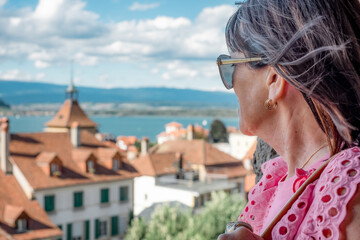 Fototapeta na wymiar Side view of mature brunette woman in summer vacation looking at lake landscape enjoying a sunny day