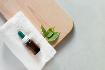 Glass dropper bottle mockup. Body care and spa. Natural cosmetics. skin care bottle.
bottle for essential oils and cosmetics lies on a white towel. Dropper. Spa still life with towel,  wooden board