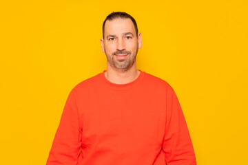Isolated photo of a handsome man with a beard, wears a casual red sweater. He has a cheerful and relaxed expression, he is happy and content with his life