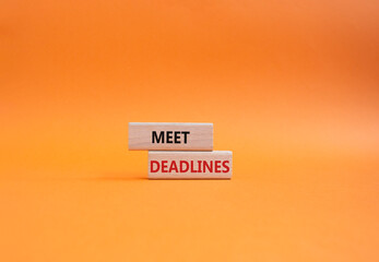 Meet Deadlines symbol. Concept word Meet Deadlines on wooden blocks. Beautiful orange background. Business and Meet Deadlines concept. Copy space