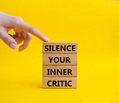 Silence your inner critic symbol. Wooden blocks with words Silence your inner critic. Beautiful yellow background. Businessman hand. Business and Silence your inner critic concept. Copy space.
