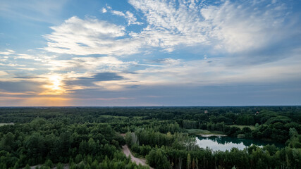 Aerial panoramic landscape over a winding forest road in Belgium, during sunset, drone shot. High quality photo