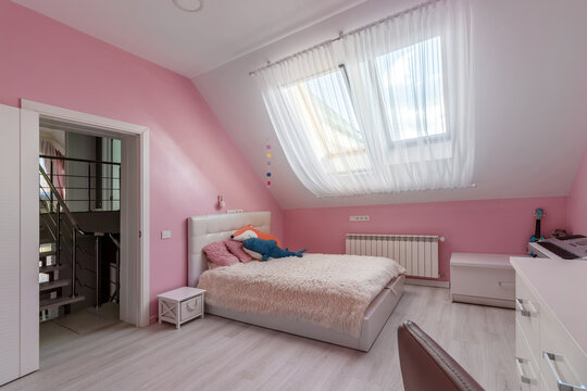 Girl bedroom with pink wall, table and toys in the attic