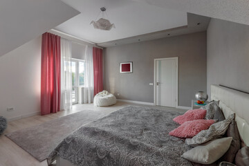 Beautiful interior design of a modern and cozy bedroom with pink pillows and curtains