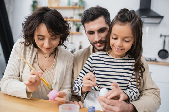 happy family smiling while coloring Easer eggs in kitchen.