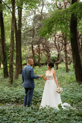 wedding walk of the bride and groom in the deciduous forest in summer