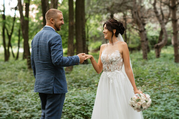 wedding walk of the bride and groom in the deciduous forest in summer