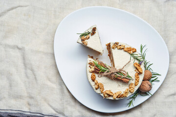 Top down view on traditional carrot cake with walnut with slice on the bright white plate