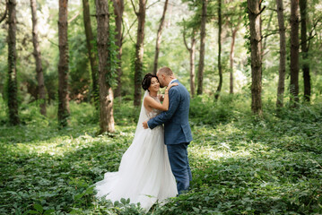 wedding walk of the bride and groom in the deciduous forest in summer