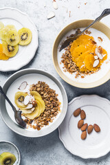 Yogurt granola bowls with kiwi and orange fruits,  top view. Healthy vegetarian breakfast meal