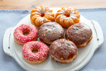 A set of donuts on a plate, glazed with frosting with pink icing and sprinkles.