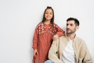 Smiling preteen girl standing near bearded father on white background.