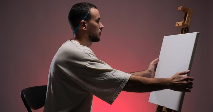 Caucasian man painter placing canvas on easel