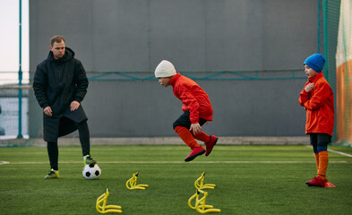 Developing speed. Boys, children, football players doing exercises, warming up before training session with coach on sport field outdoors. Sport, childhood, active lifestyle, hobby, sport club concept