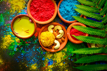 top view of colorful traditional holi powder in bowls isolated on dark background.Space for text . happy holi.Concept Indian color festival called Holi